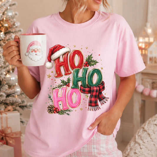 “Ho Ho Ho” in red, green and pink letters with gold outlines, a Santa hat, red and black buffalo plaid scarf, holly, pinecones and gold stars.