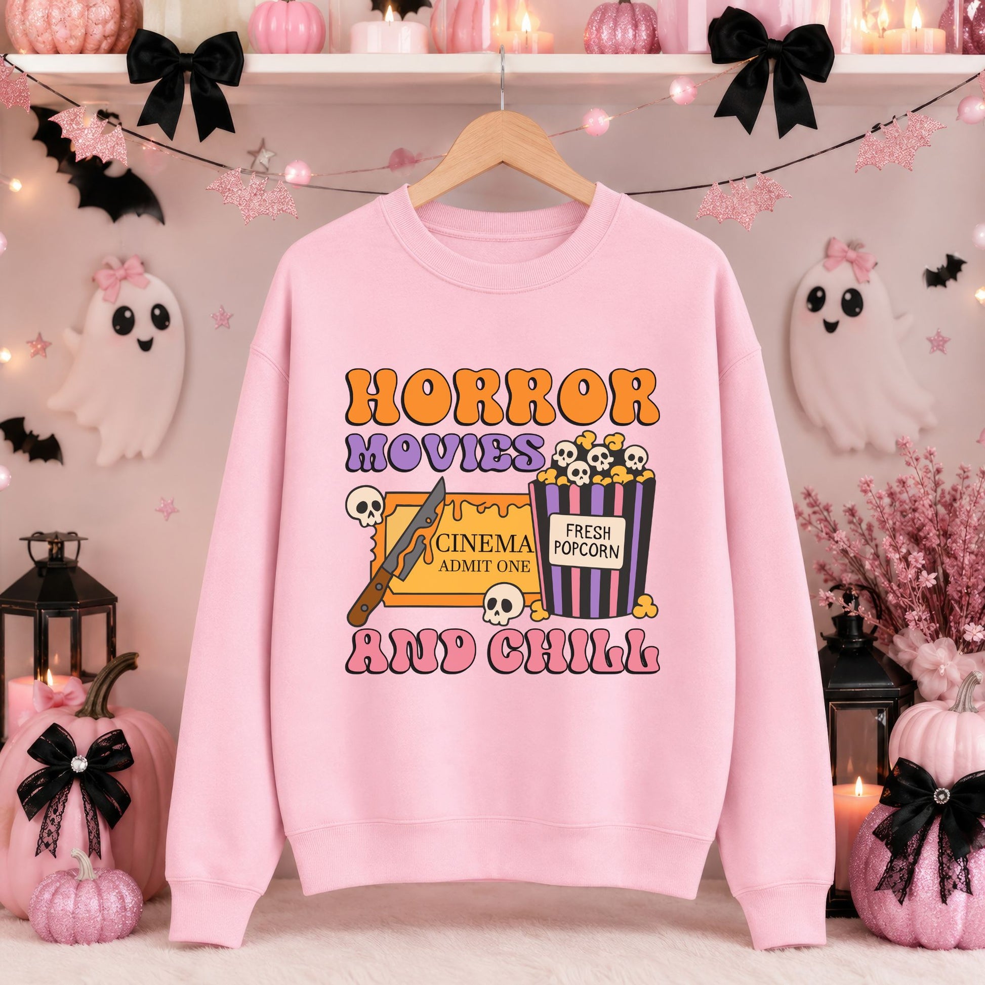 Colorful Horror Movies and Chill Halloween DTF transfer featuring groovy orange, purple and pink lettering with a cinema ticket, striped popcorn bucket filled with skulls, horror knife and scattered skull accents on a pink sweatshirt mockup.