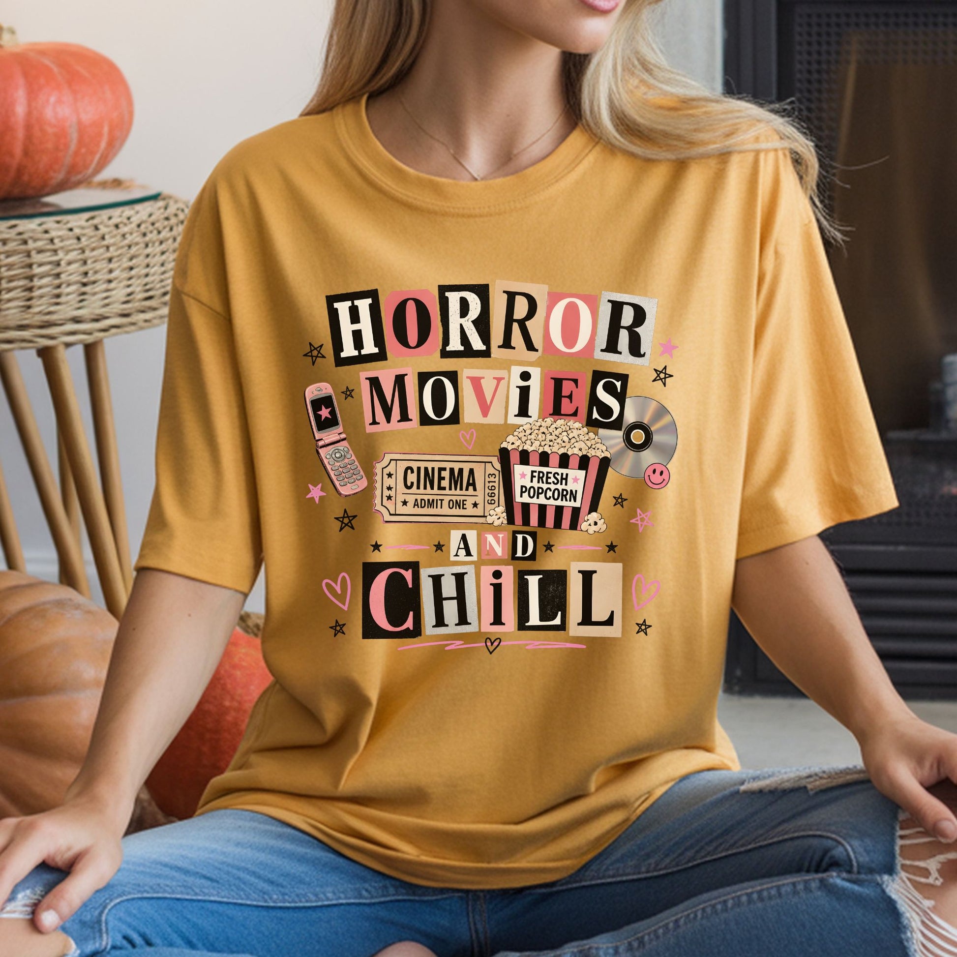 Retro Horror Movies and Chill DTF transfer featuring colorful ransom-style lettering with a cinema ticket, striped popcorn bucket, CD, pink flip phone, stars and heart accents on a mustard yellow T-shirt mockup.