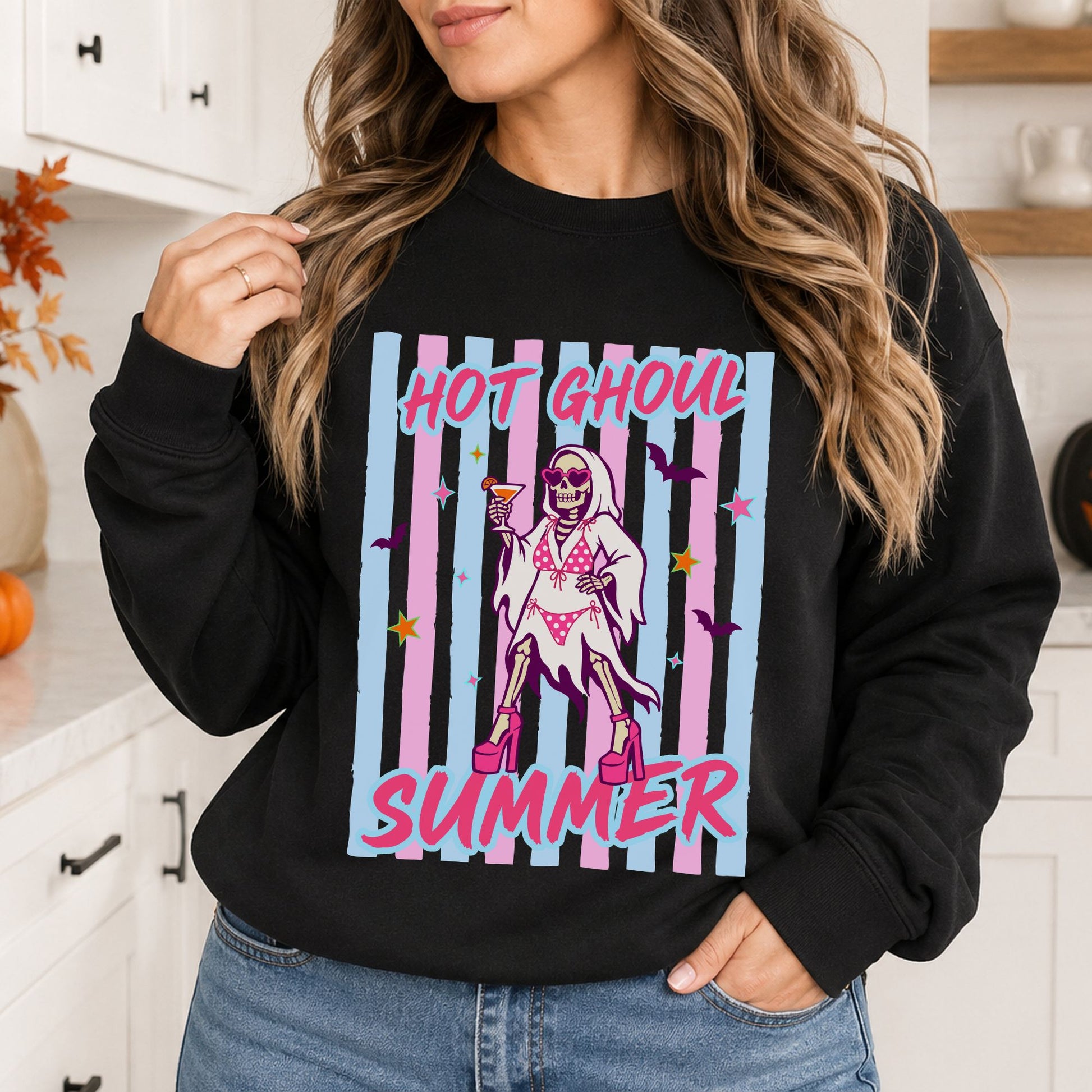 Black sweatshirt mockup featuring a skeleton in a pink bikini and heels with a cocktail, pink and blue stripes, and the phrase Hot Ghoul Summer.