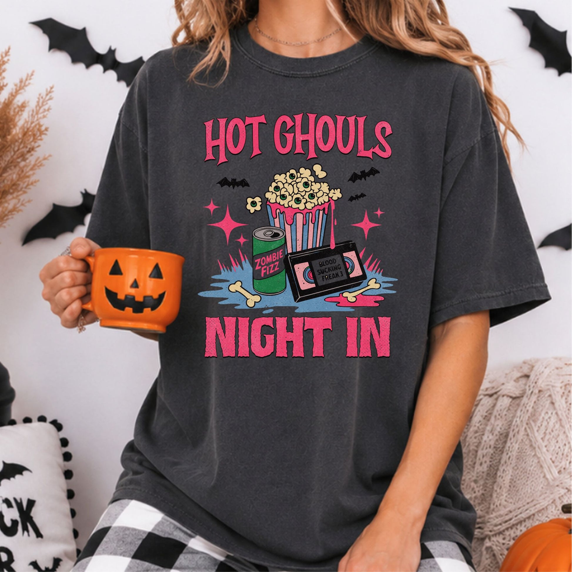 Hot Ghouls Night In Halloween DTF transfer featuring a striped popcorn bucket filled with eyeball popcorn, a green Zombie Fizz soda can, retro VHS tape, bones, dripping pink slime, bats and bright vintage-inspired accents on a dark gray T-shirt mockup.