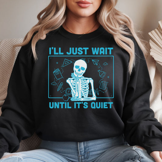 Funny teacher skeleton design featuring bright blue lettering, classroom doodles, school supplies, and the phrase I’ll Just Wait Until It’s Quiet on a black sweatshirt.