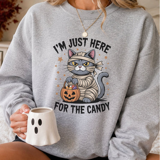 I'm Just Here For The Candy Halloween DTF transfer featuring a grumpy gray cat dressed as a mummy holding a jack-o-lantern candy bucket with stars and spooky details
