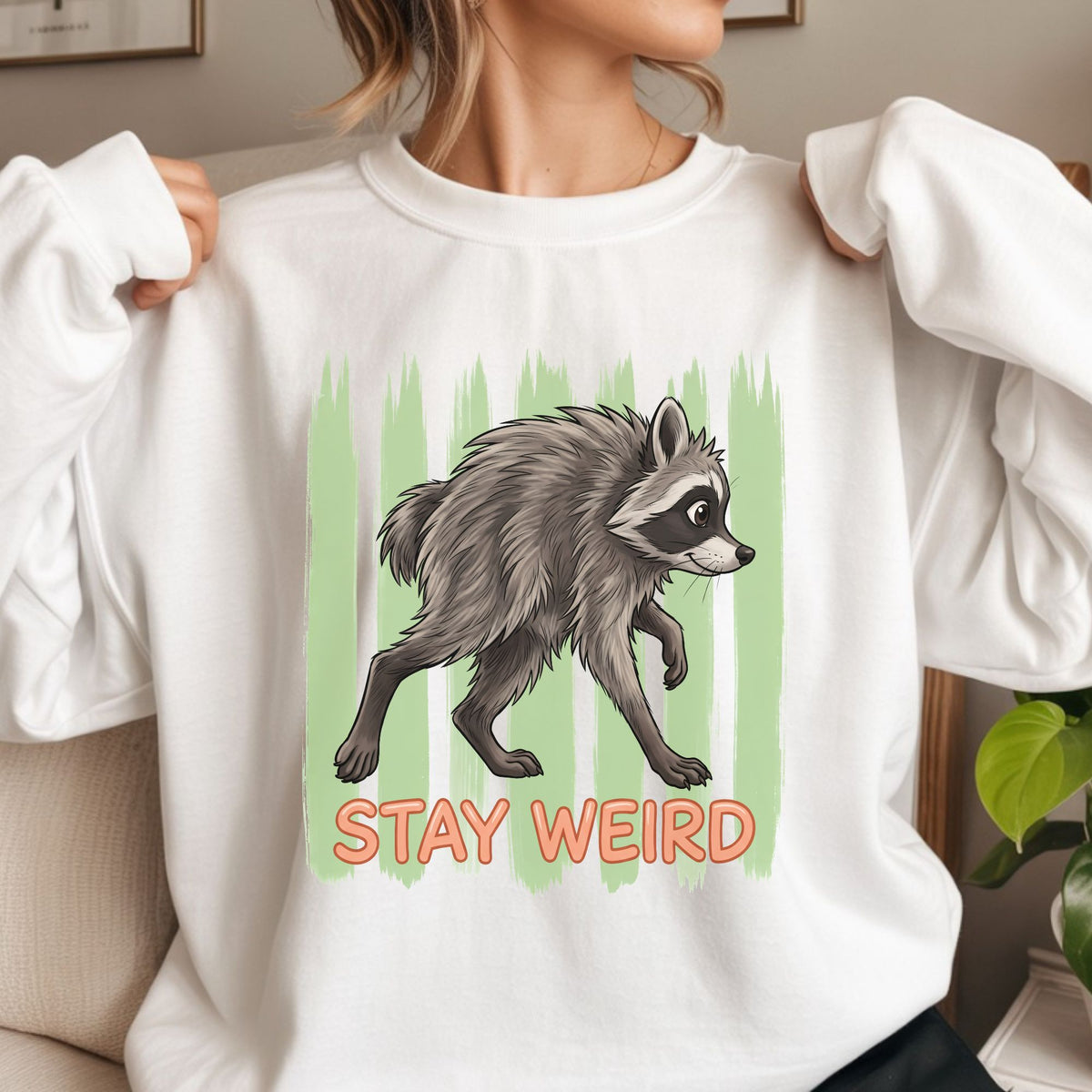 Jimothy Stay Weird raccoon DTF transfer featuring the famous gray raccoon with a green distressed stripe background and bold orange lettering for funny raccoon shirts, sweatshirts, tote bags, and quirky graphic tees.