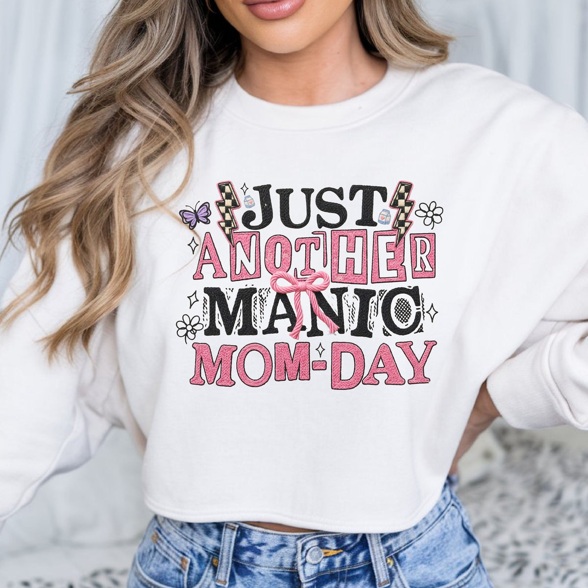 Just Another Manic Mom-Day DTF transfer featuring pink and black faux embroidery lettering, checkerboard lightning bolts, bow, butterfly, flowers, and playful mom graphics for funny mom shirts and sweatshirts.