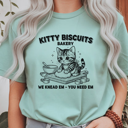 Cute kitten kneading dough with the phrase Kitty Biscuits Bakery We Knead Em You Need Em, funny cat baking design perfect for cat lovers, bakers, pet parents, and animal humor fans