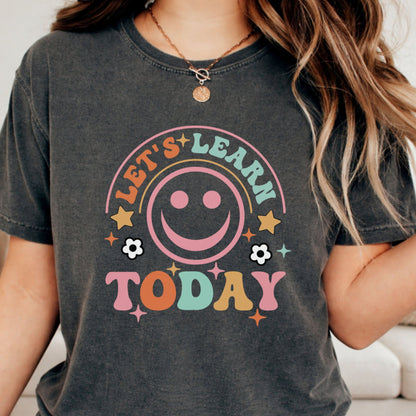 Let’s Learn Today school design featuring a large retro pink smiley face, colorful vintage lettering, stars, sparkles, and flower accents for teacher shirts and classroom apparel.