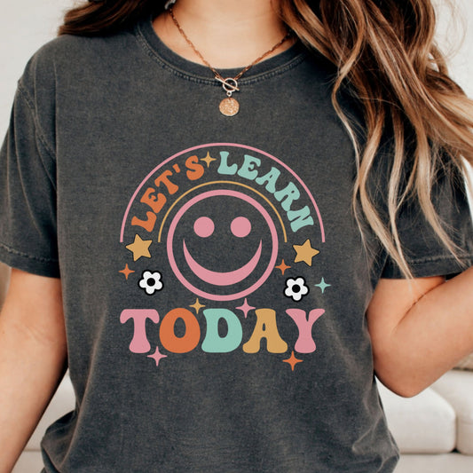 Let’s Learn Today school design featuring a large retro pink smiley face, colorful vintage lettering, stars, sparkles, and flower accents for teacher shirts and classroom apparel.