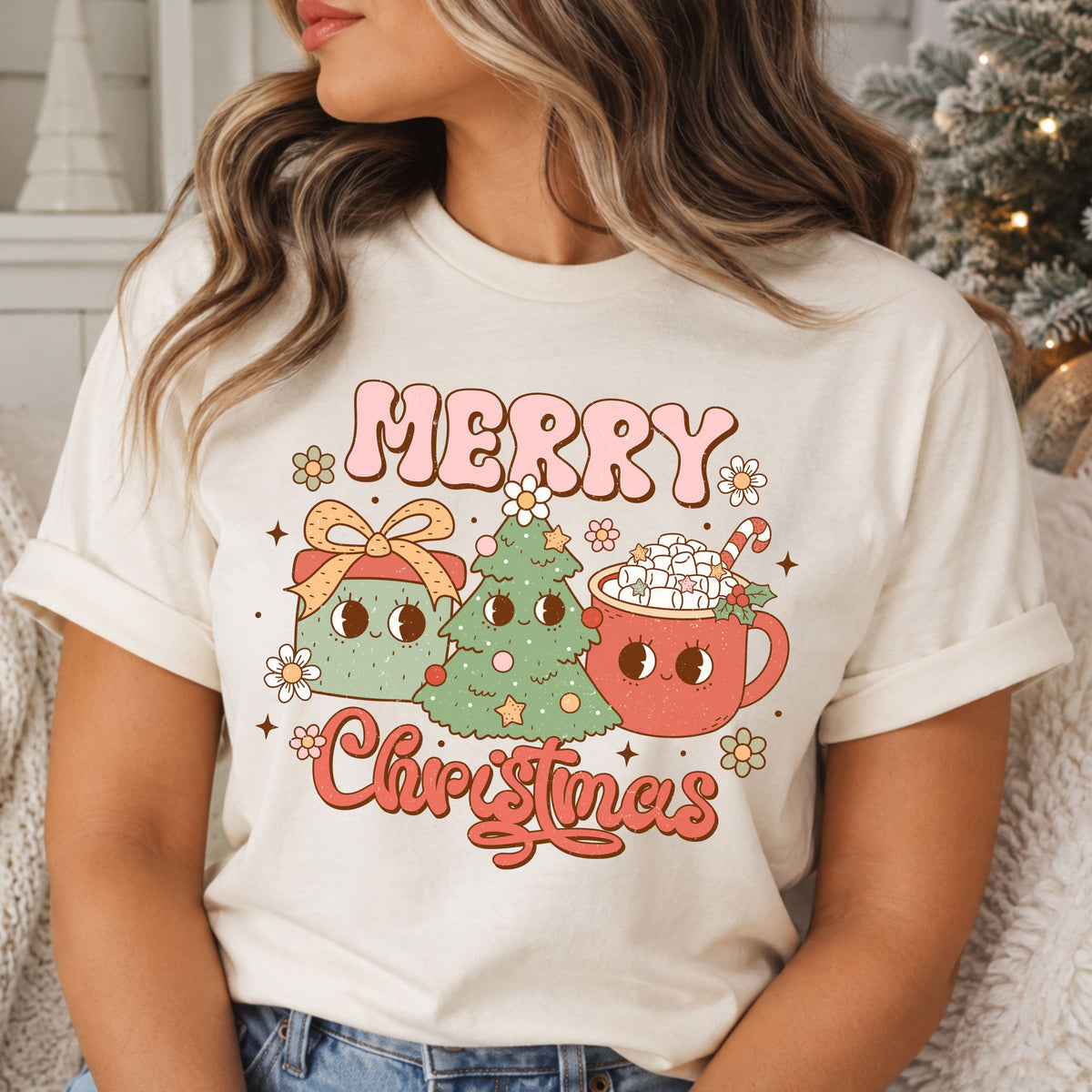 Merry Christmas in pink bubble letters and coral script around a smiling sage green tree, gift with a peach bow and coral hot cocoa mug topped with marshmallows, surrounded by daisies and stars.
