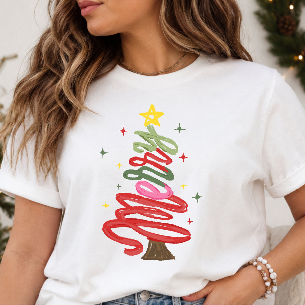“Merry” in red, pink and green textured script arranged as a Christmas tree, topped with a yellow star and surrounded by colorful sparkles.