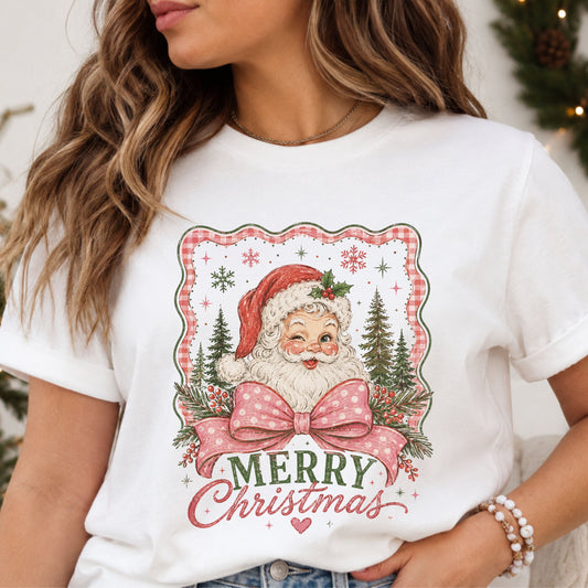 “Merry Christmas” beneath a winking Santa in a red hat, with a pink polka dot bow, evergreen trees and berry branches inside a distressed pink gingham frame.