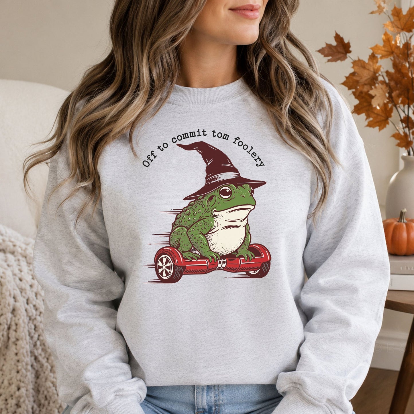Funny Off to Commit Tomfoolery Halloween DTF transfer featuring a green frog wearing a pointed witch hat while riding a red hoverboard, displayed on a gray sweatshirt mockup.