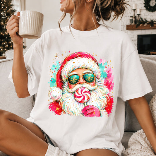 Santa wearing teal aviator sunglasses with gold snowflakes, holding a pink and white peppermint lollipop, with pink and teal paint splashes and gold stars.