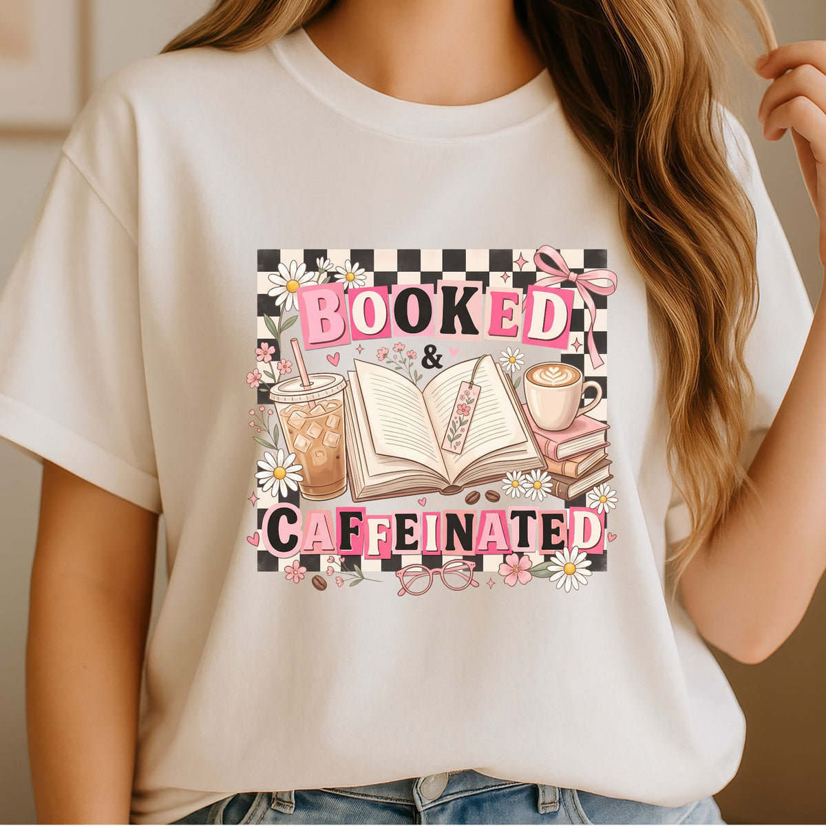 Booked & Caffeinated DTF transfer featuring pink retro lettering, black and white checkerboard, open books, iced coffee, hot coffee, daisies, flowers, glasses, and a pink bow for book lover shirts, reader sweatshirts, and bookish apparel.