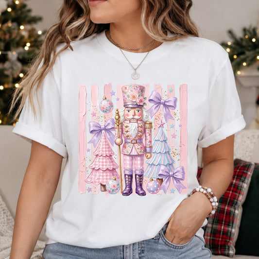 Pink floral nutcracker with purple boots, pastel Christmas trees, lavender bows and floral ornaments against pink brushstroke stripes with faux gold glitter accents.
