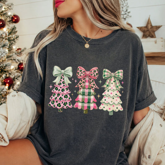 Three Christmas trees in pink, green and cream with leopard print, plaid and polka dots, topped with oversized mint, leopard and plaid bows, surrounded by stars.