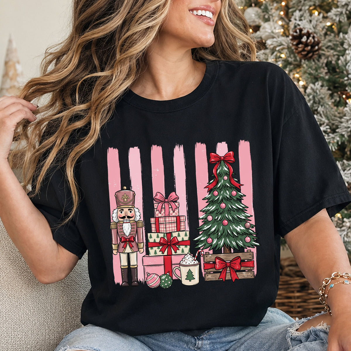 Pink nutcracker beside stacked gifts, hot cocoa and a Christmas tree in a wooden crate, decorated with red bows and pink ornaments against pink brushstroke stripes.