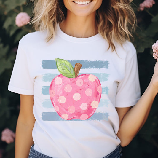 Pink polka dot apple teacher design featuring a hand-painted apple with a green leaf layered over soft blue brushstroke stripes for cheerful back-to-school shirts, sweatshirts, hoodies, and ready-to-press DTF transfers.