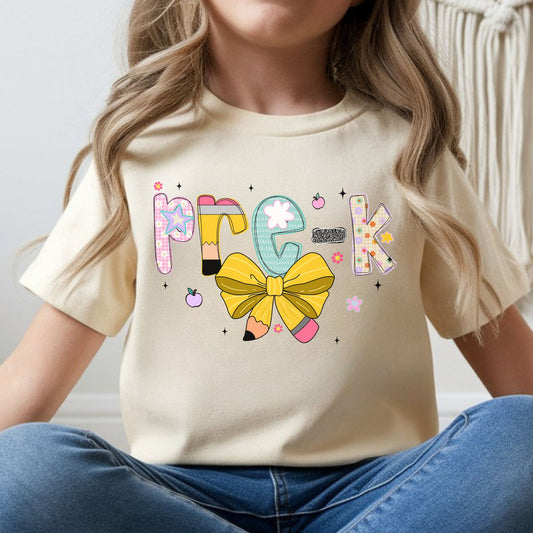 Pre-K back-to-school design featuring colorful patterned letters, pencil accents, a large yellow pencil bow, flowers, apples, and playful preschool details for kids shirts.