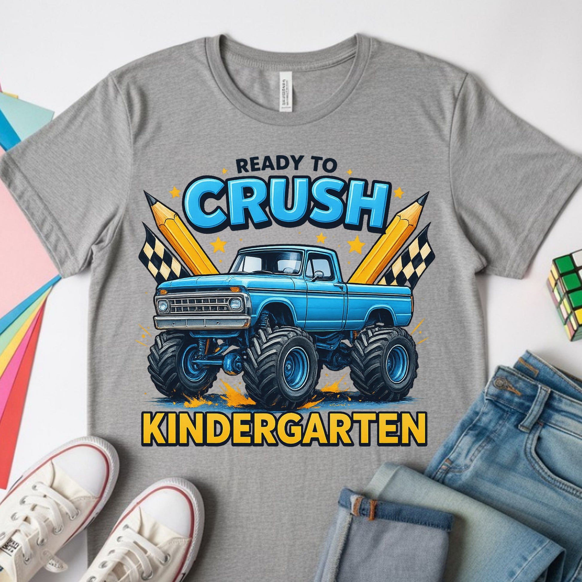 Ready to Crush Kindergarten back-to-school design featuring a blue monster truck with oversized tires, pencils, and checkered flags for first day of kindergarten shirts.