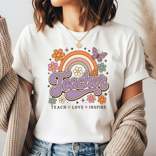 Retro Teacher DTF transfer featuring purple script lettering, a muted rainbow, colorful flowers, butterfly, and the phrase Teach Love Inspire.