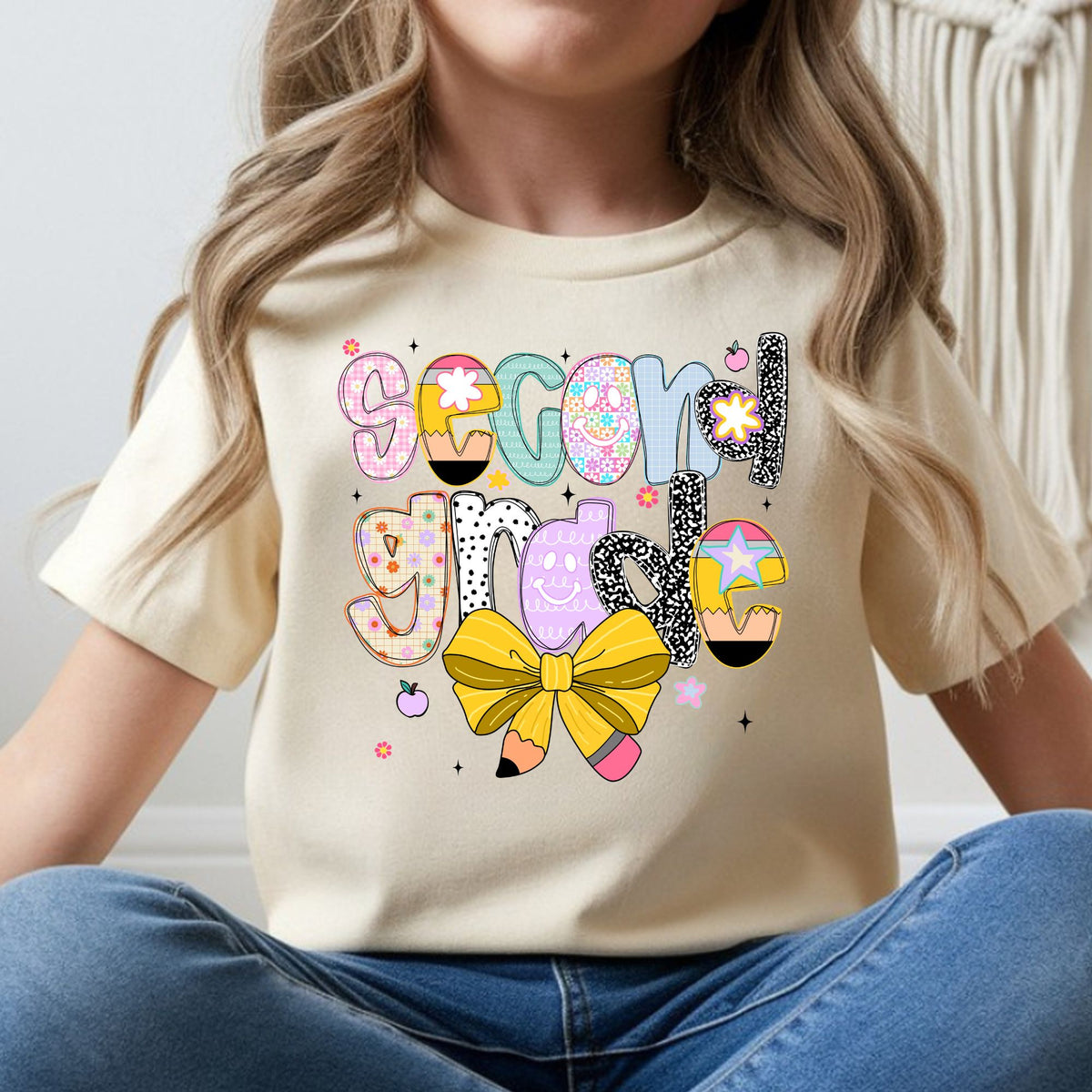 Second Grade back-to-school design featuring colorful patterned letters, pencil accents, a yellow pencil bow, flowers, apples, and playful classroom details for kids shirts.