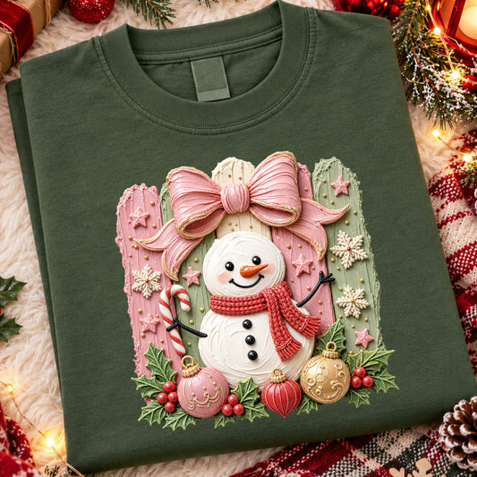 Smiling snowman with a red faux knit scarf and candy cane beneath a large pink bow, with pink and sage stripes, snowflakes, holly and colorful ornaments.