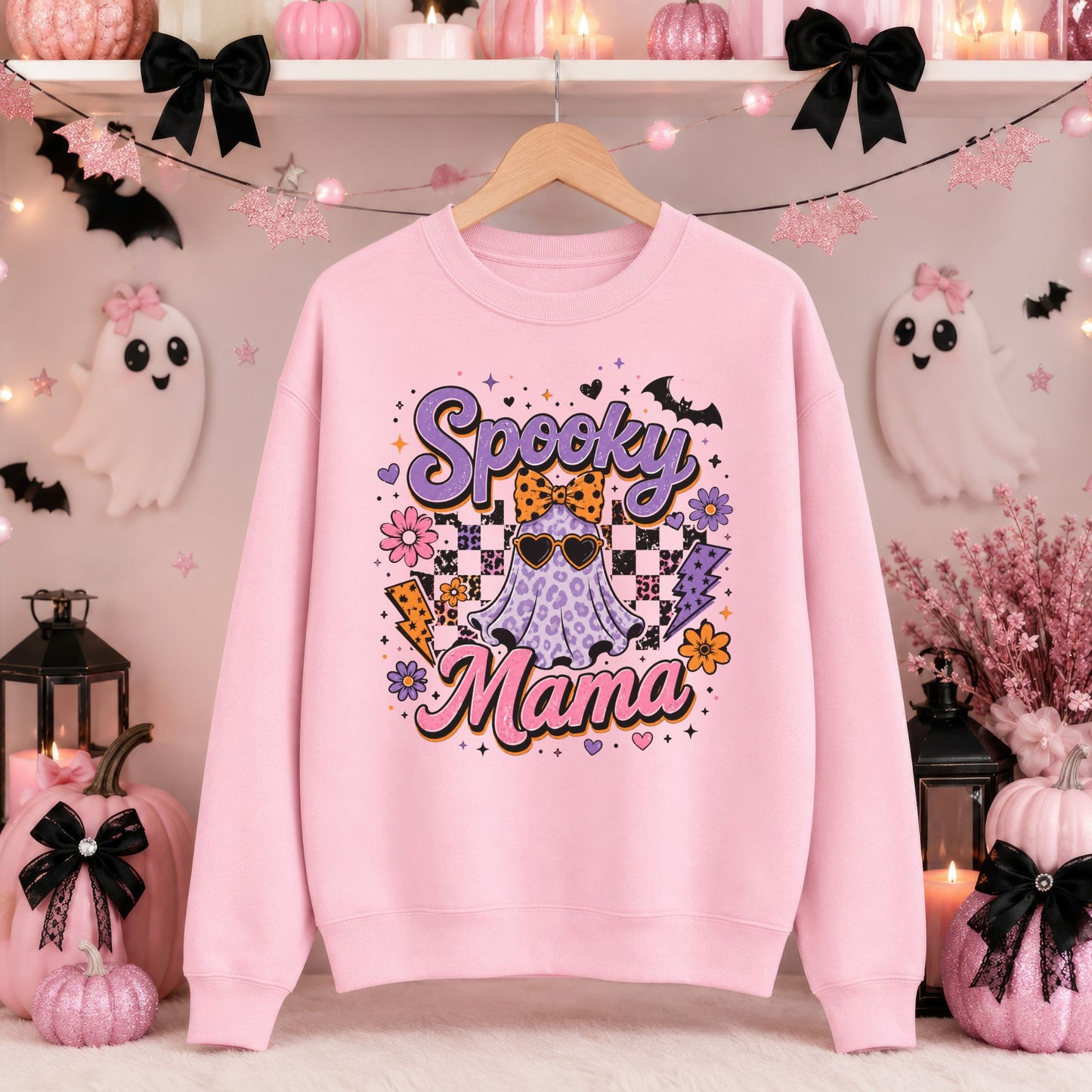 Spooky Mama Halloween DTF transfer featuring a purple leopard-print sheet ghost wearing heart-shaped sunglasses and an orange leopard bow, surrounded by checkerboard accents, bats, colorful flowers, hearts, stars and lightning bolts on a pink sweatshirt mockup.