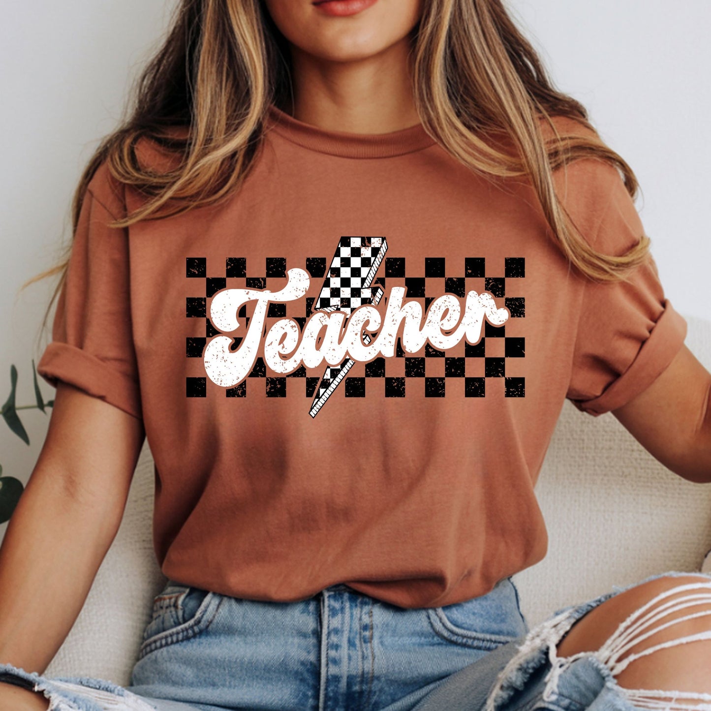 Retro Teacher design featuring distressed white script lettering, a black-and-white checkerboard background, and a bold checkerboard lightning bolt for teacher shirts and classroom apparel.