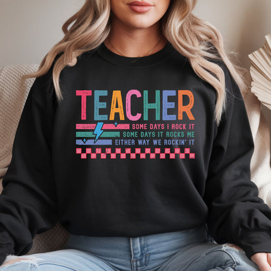 Funny teacher design featuring distressed colorful lettering, retro stripes, a lightning bolt, checkerboard accents, and the phrase Some Days I Rock It, Some Days It Rocks Me, Either Way We Rockin’ It.