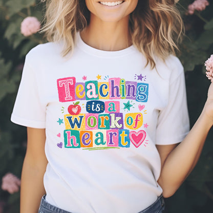 Teaching Is a Work of Heart teacher design featuring bright multicolor block lettering, an apple, hearts, stars, and playful classroom accents for teacher shirts and school apparel.