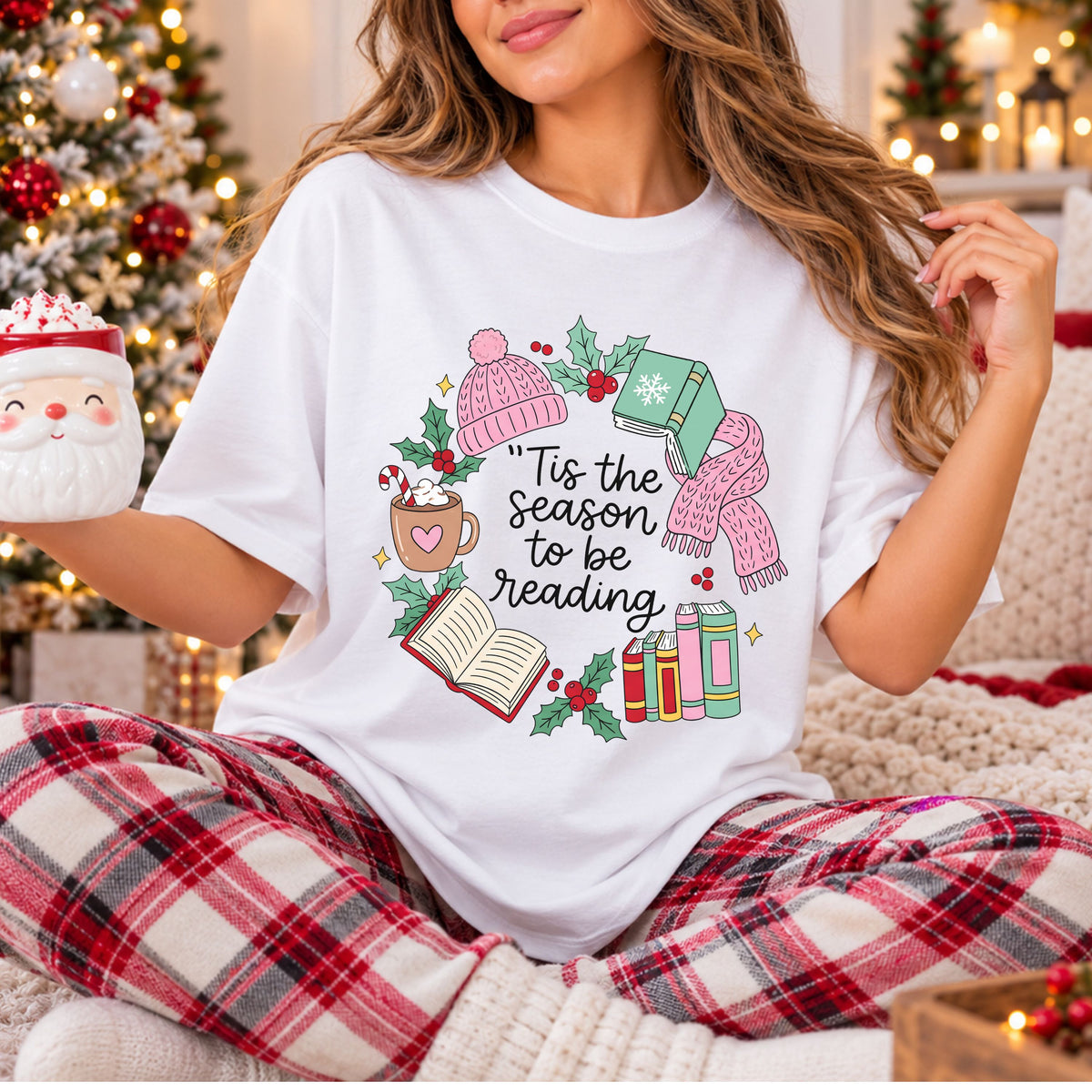 “Tis the season to be reading” in black script, framed by books, a pink knit hat and scarf, hot cocoa with a candy cane, holly and yellow stars.