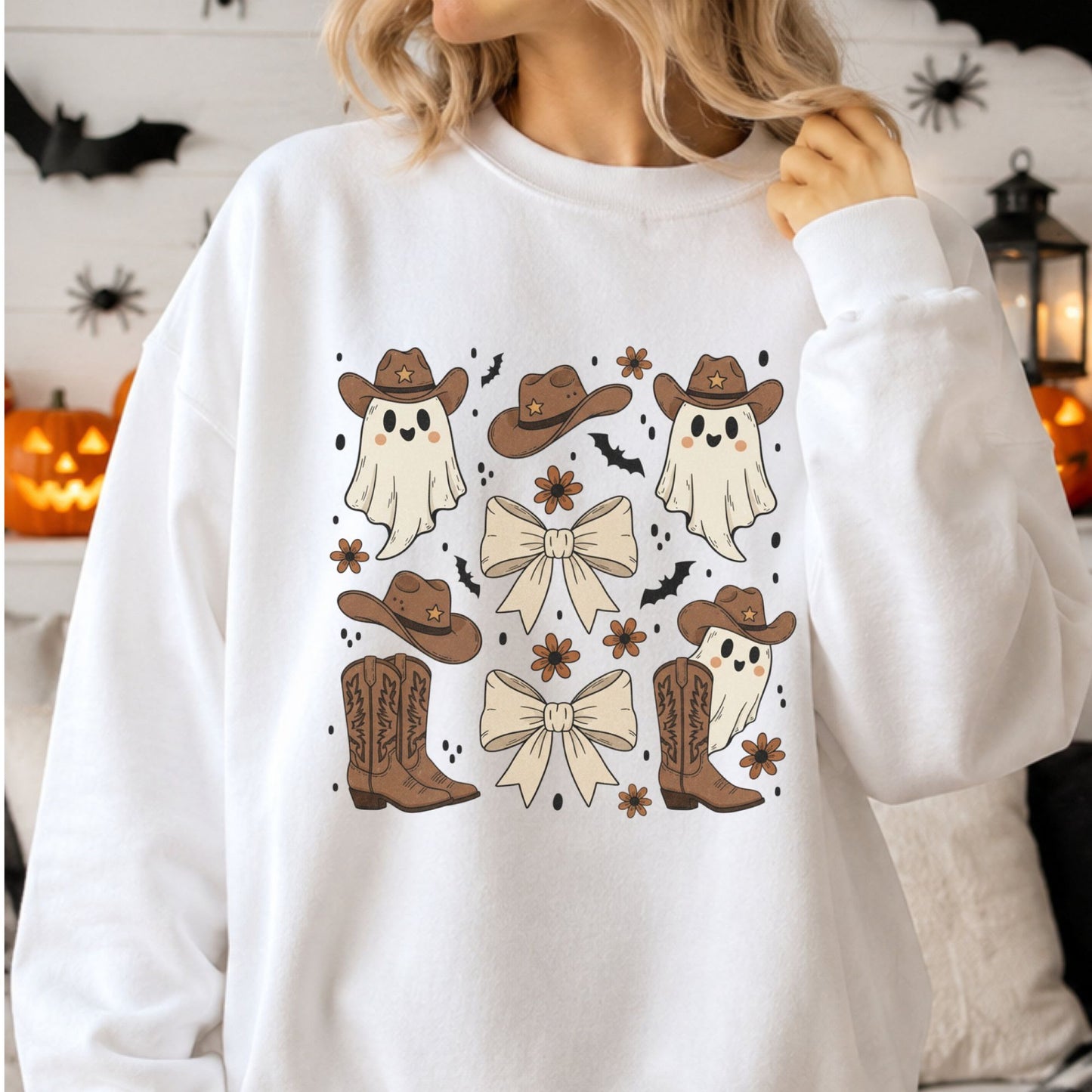Cute Western Halloween DTF transfer featuring three smiling ghosts in brown cowboy hats with cowgirl boots, cream bows, bats and retro flowers on a white sweatshirt mockup.