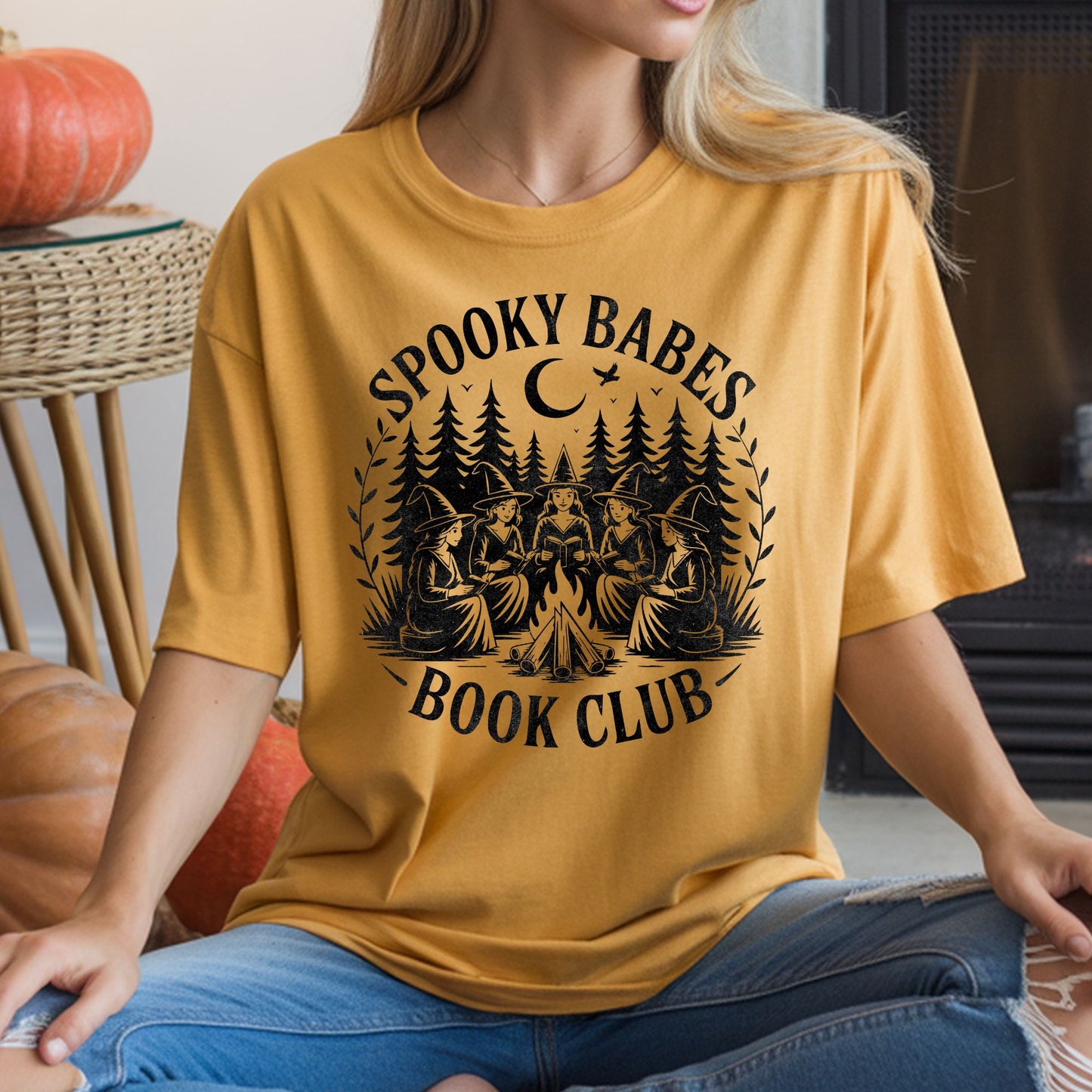 Spooky Babes Book Club Halloween DTF transfer featuring five witches reading together around a campfire in a dark pine forest beneath a crescent moon, with vintage distressed black artwork on a mustard yellow T-shirt mockup.
